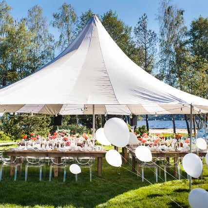 Event RentalsA white event tent set outdoors on a clear day covering set tables surrounded by balloons.