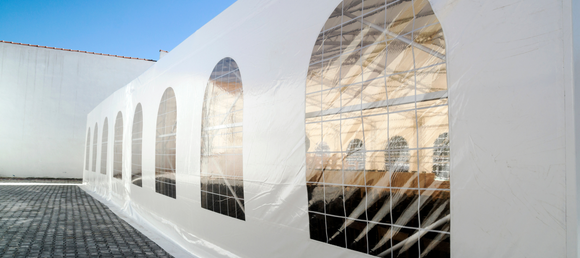 A white event tent setup outdoors on a clear day.