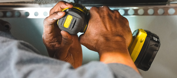 A close-up of a yellow power drill being used.